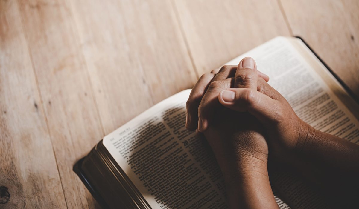 Spirituality and religion, Hands folded in prayer on a Holy Bible in church concept for faith.